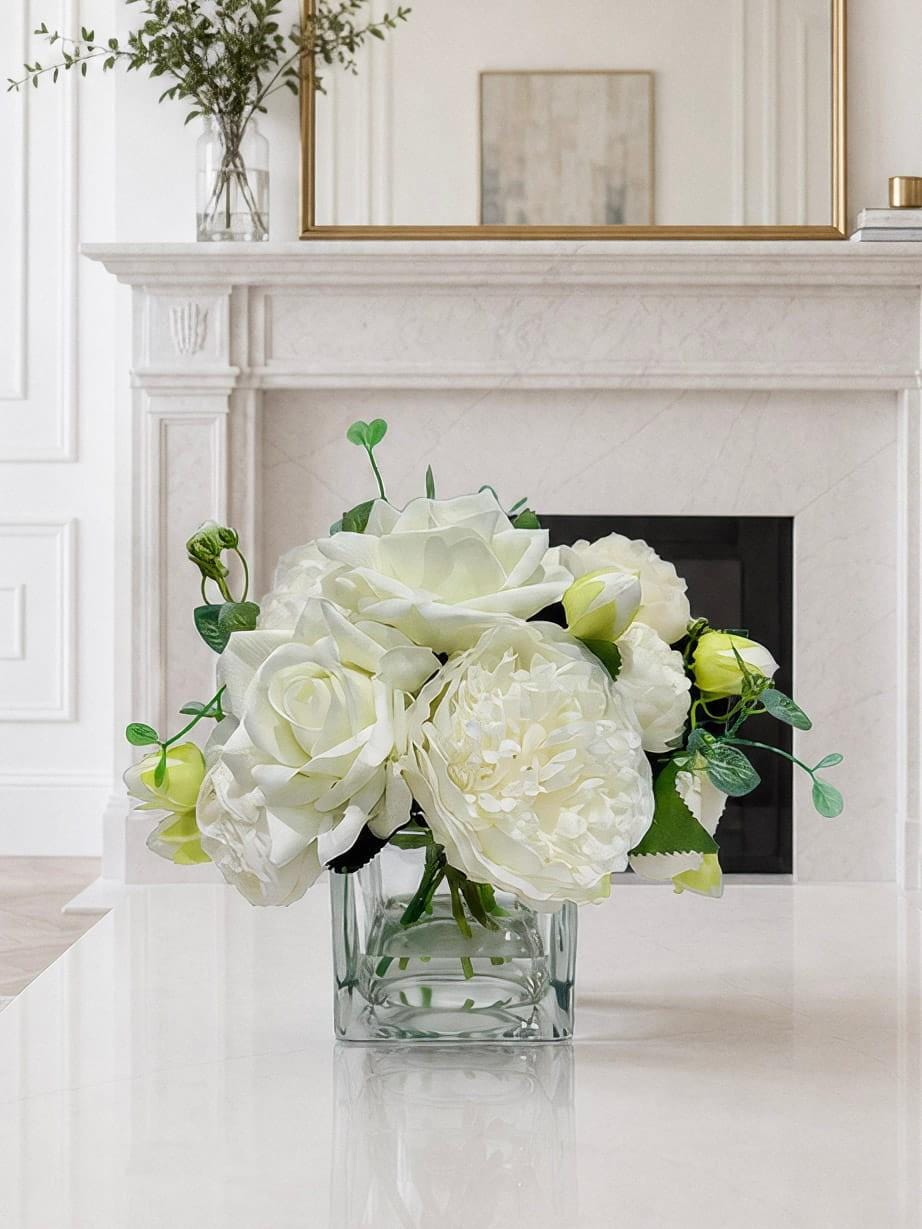 White real touch rose peony hydrangea centerpiece in a glass vase styled on a mantel