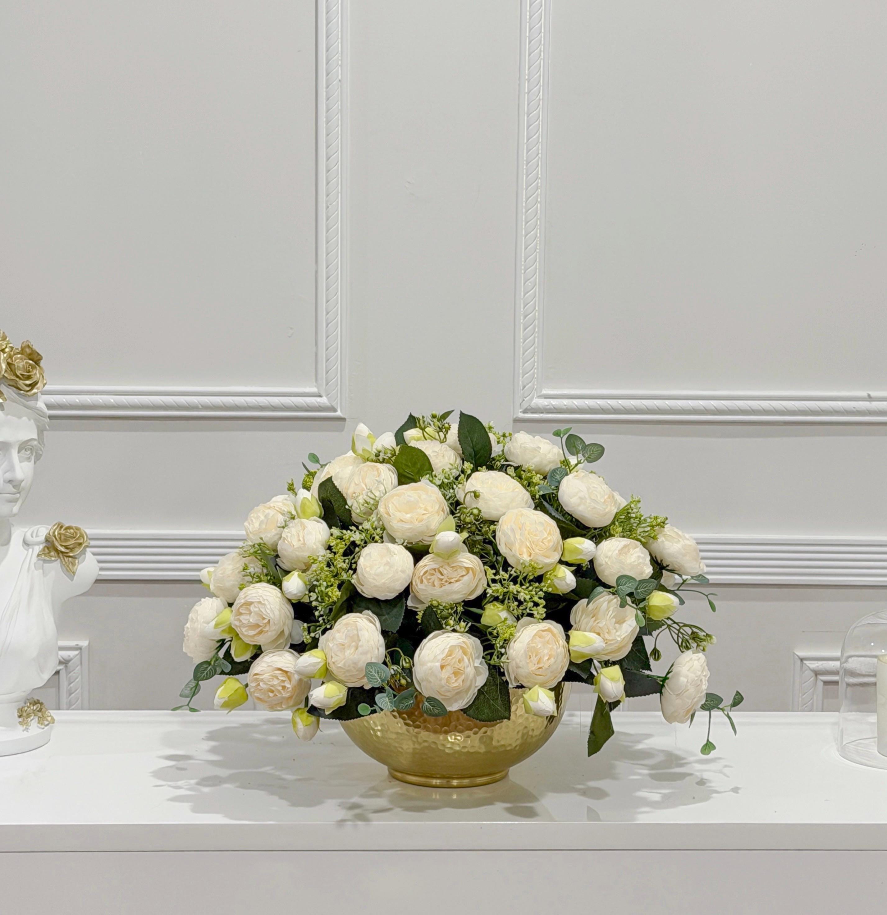 White peony arrangement with green foliage in gold vase