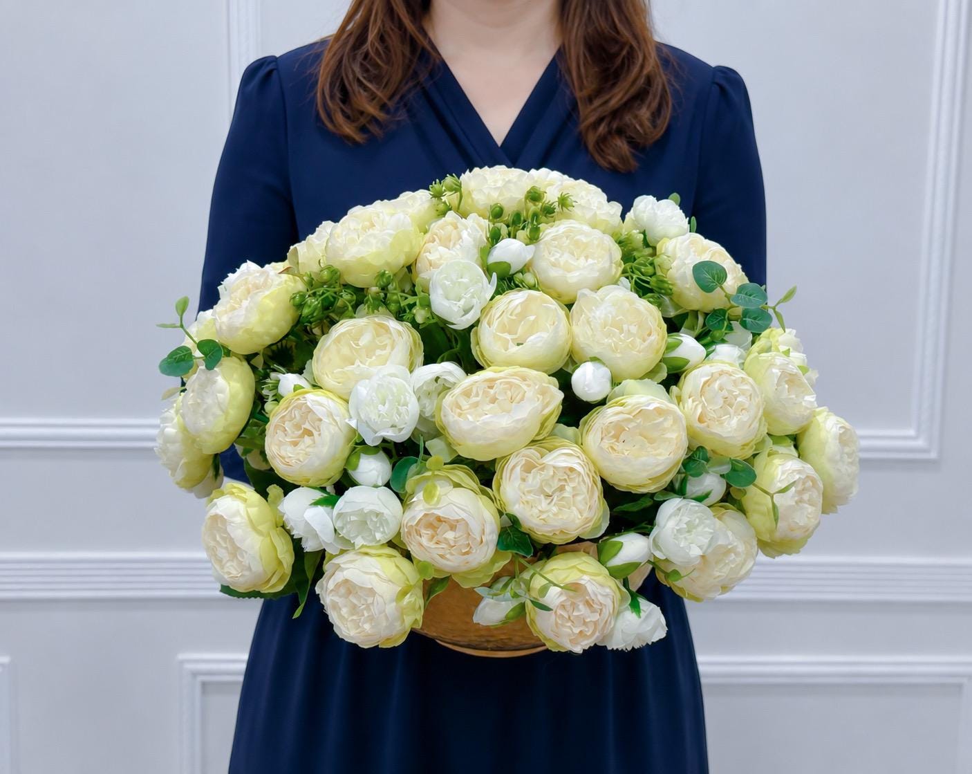 White and green ombre peony centerpiece held by a floral designer Main image