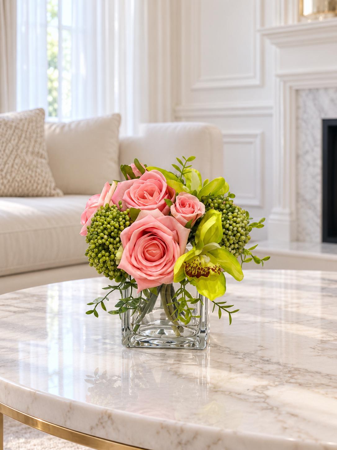 Pink and green real touch rose and orchid faux floral centerpiece in a glass vase