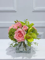 Pink and green real touch rose and orchid faux floral centerpiece in a glass vase