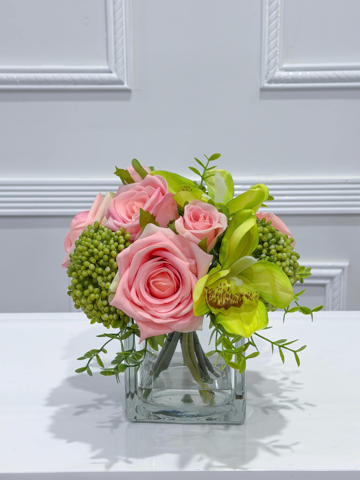 Pink and green real touch rose and orchid faux floral centerpiece in a glass vase