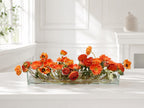 Orange ranunculus poppy daisy fall centerpiece in a clear glass vase