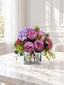 Purple peony rose and hydrangea faux floral centerpiece in a clear glass vase