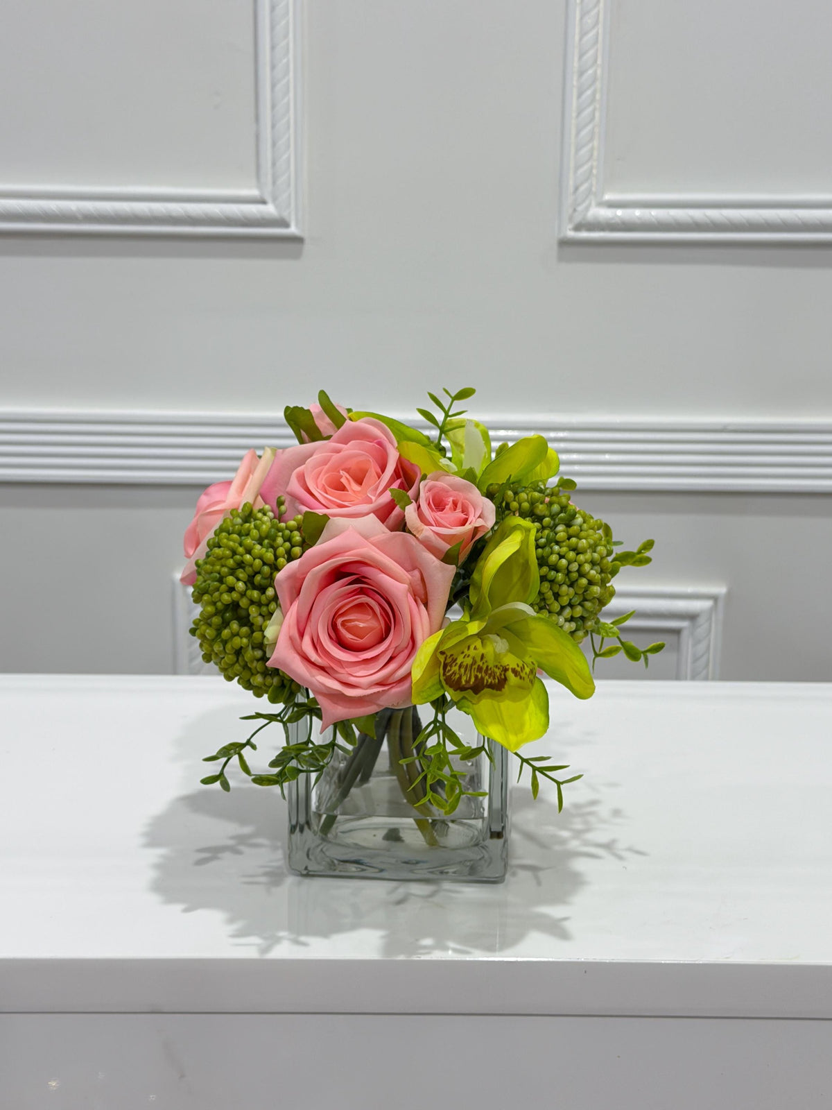 Pink and green real touch rose and orchid faux floral centerpiece in a glass vase