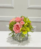 Pink and green real touch rose and orchid faux floral centerpiece in a glass vase