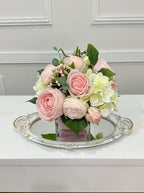 Real touch pink rose and faux hydrangea arrangement in pink cube glass vase on mirrored tray, studio photo