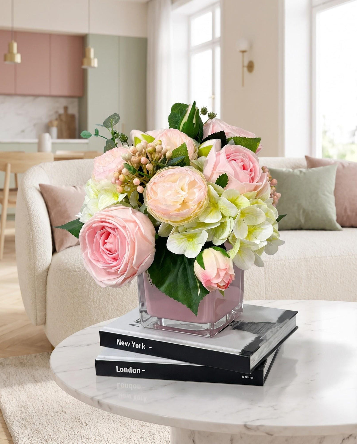 Real touch pink rose and faux hydrangea arrangement in pink cube glass vase on coffee table books in modern living room